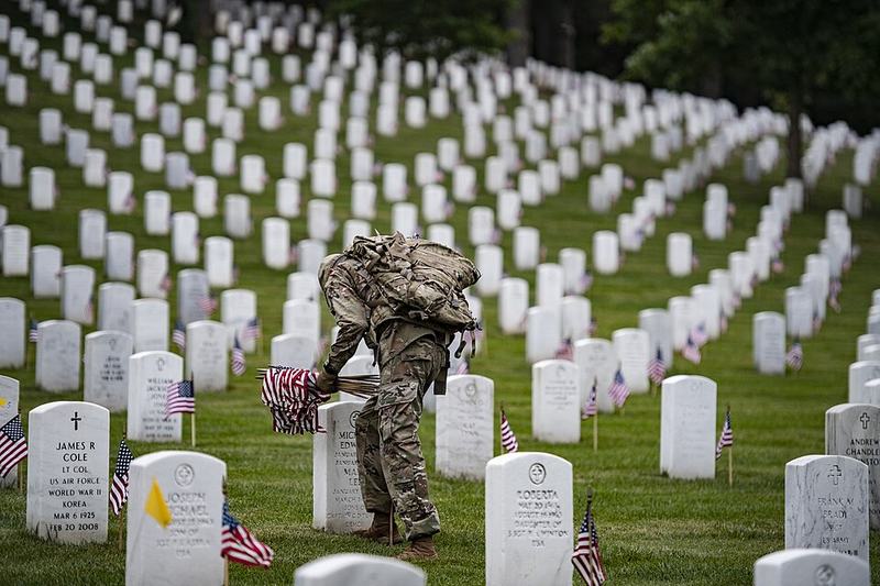 Soldier places flags at gravesights at Arlington