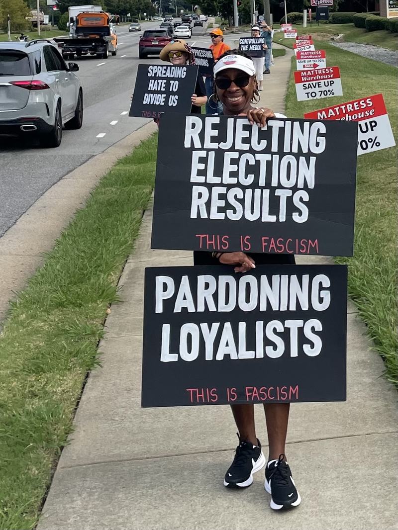 Protester with signs "Rejecting Election Results" and "Pardoning Loyalists"