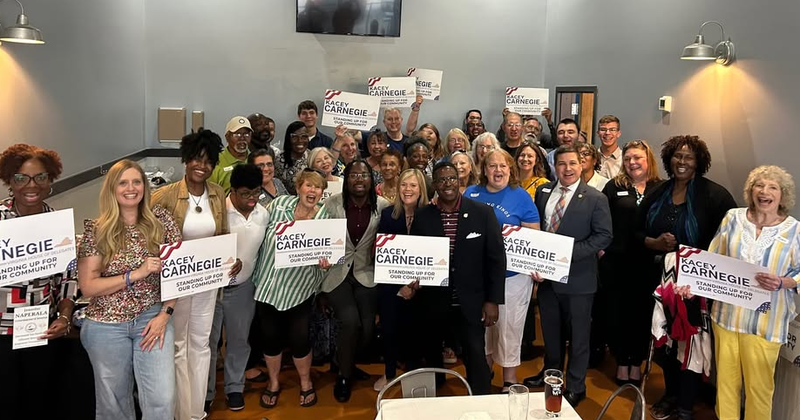 Group photo of Kacey Carnegie and several supporters inside space that seems to be a restaurant